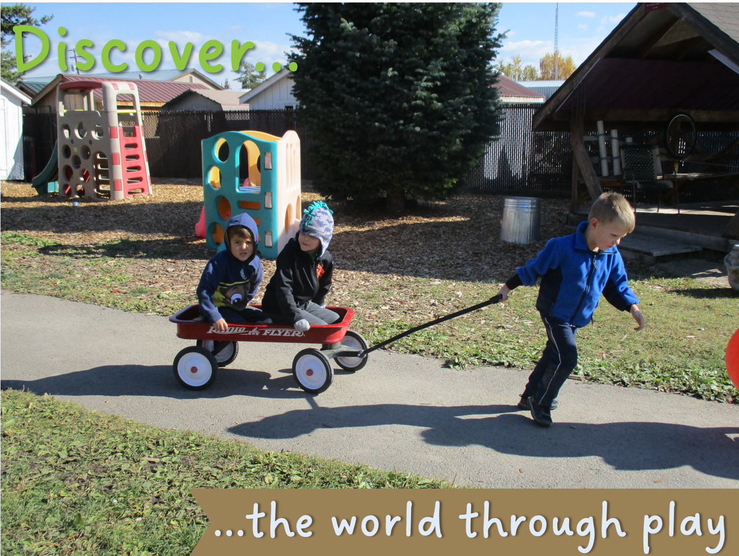 A preschool-age boy pulls two other young boys in a red wagon.